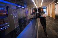 pexels photo 1181316 1181316 A woman using a laptop navigating a contemporary data center with mirrored servers.